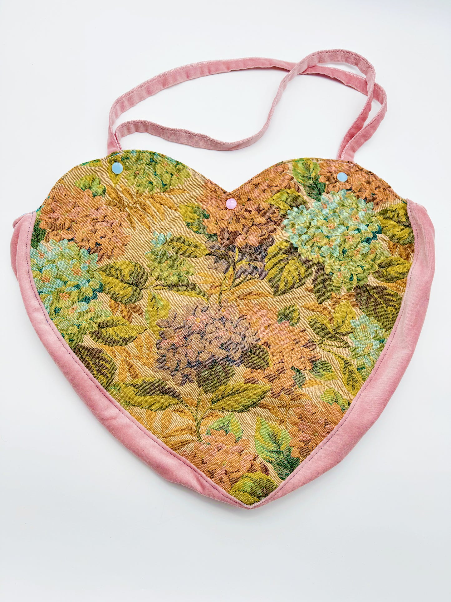 One-of-a-kind custom heart introspective bag by Everythang Dope, wearable art accessory. A custom heart-shaped tapestry bag with floral patterns and a pink trim.