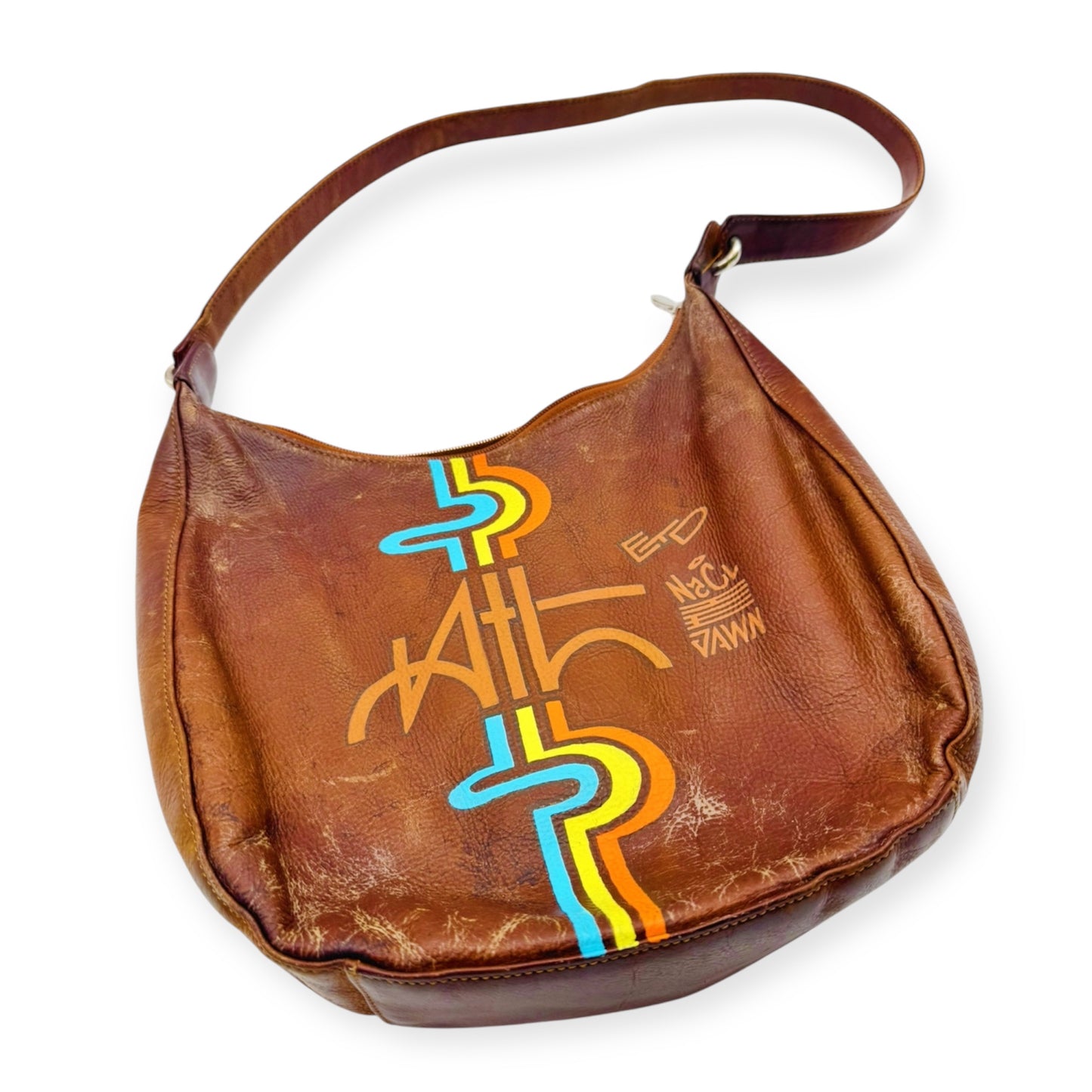 A brown leather handbag with multicolored geometric patterns and text on the front. Vintage leather bag painted with MARTA-inspired graffiti art by Everythang Dope.
