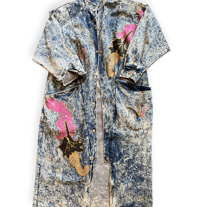 A long denim trench coat with a floral pattern on the sleeves and a vintage wash effect. Acid wash trench coat from Everythang Dope, longline vintage 80s style outerwear.