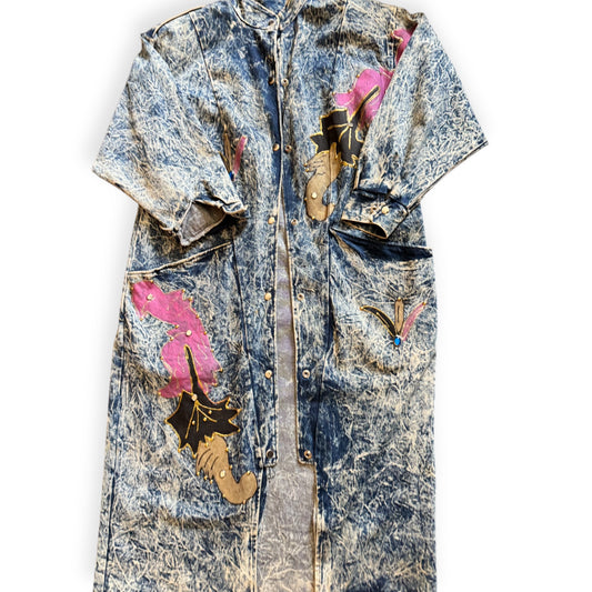 A long denim trench coat with a floral pattern on the sleeves and a vintage wash effect. Acid wash trench coat from Everythang Dope, longline vintage 80s style outerwear.