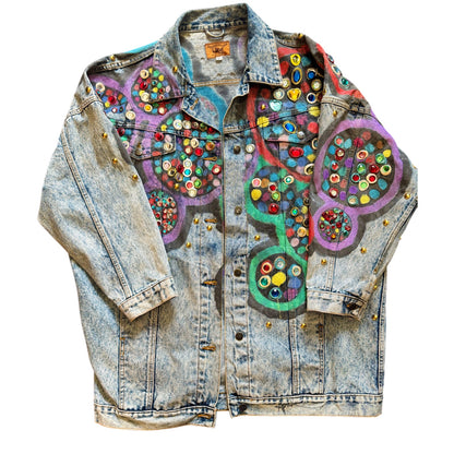 A bedazzled denim jacket with multicolored geometric patterns and decorative elements.