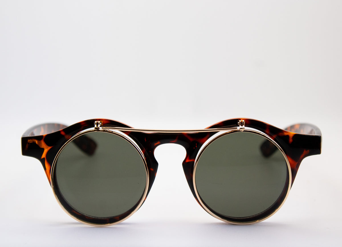 Front view of vintage Dwayne Wayne style flip-up sunglasses with green tinted lenses and a tortoise shell frame displayed by Everythang Dope. dwayne wayne flip up sunglasses, vintage tortoise shell flip up sunglasses green lens
