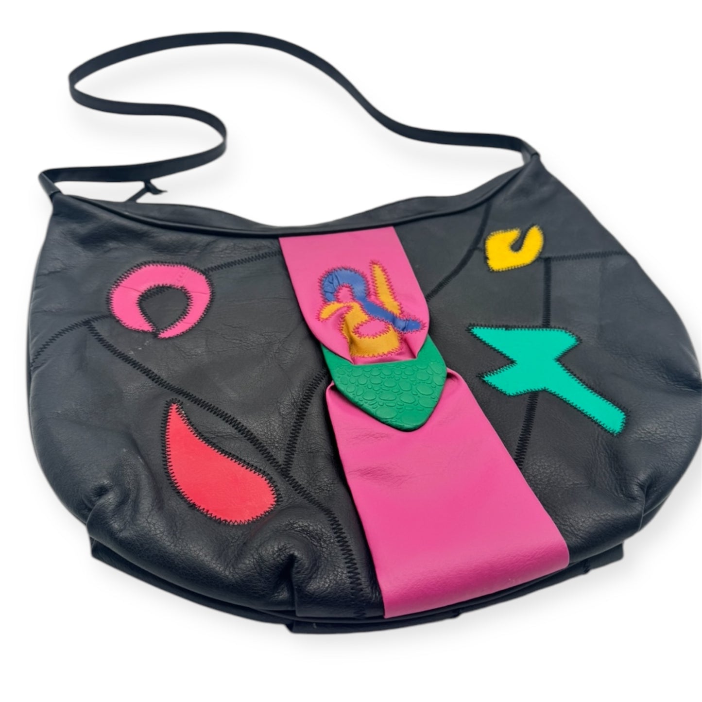A vintage leather handbag with black, pink, green, and multicolored abstract patterns and shapes on the surface.