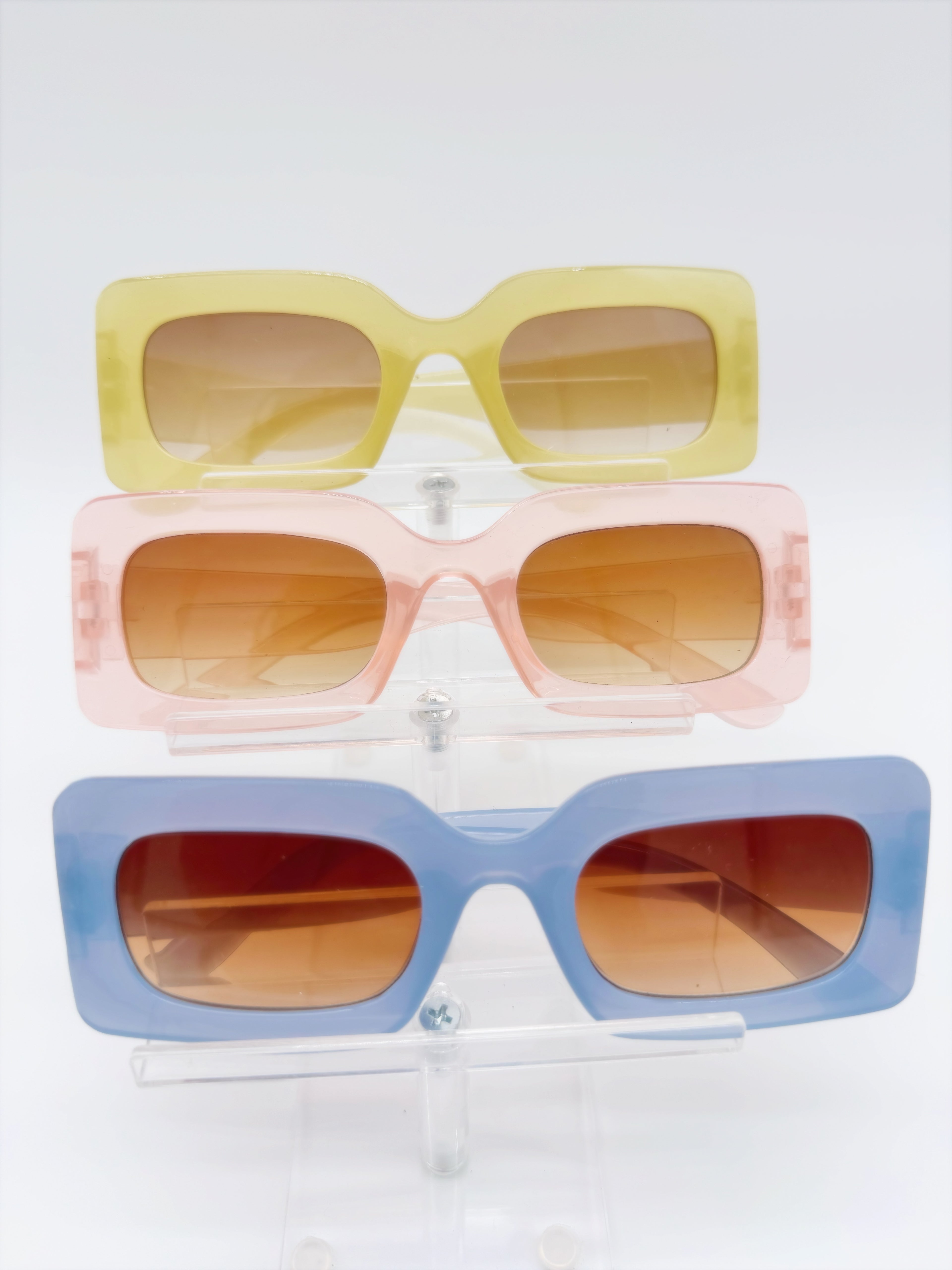 Three pairs of square-framed sunglasses in yellow, pink, and blue colors displayed against a white background.