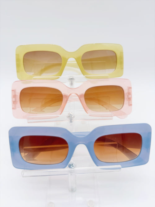 Three pairs of square-framed sunglasses in yellow, pink, and blue colors displayed against a white background.