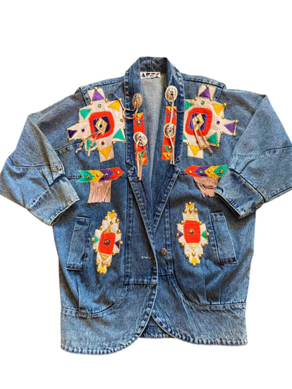 An oversized long denim jacket with colorful floral embroidery and decorative details on the collar and sleeves. Vintage denim jacket with Aztec multicolor pattern, 90s retro outerwear by Everythang Dope.